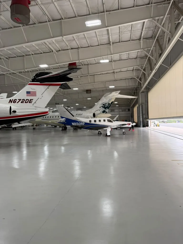 Business jets parked inside a spotless hangar maintained by the Excel Facility Maintenance team
